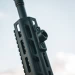Närbild av en svart Spartan M-Lok adapter monterad på ett gevärs handskydd med M-Lok system.