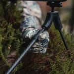 Närbild på en jägare som justerar benen på en Spartan Springbok bipod i kolfiber ute i terrängen.