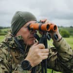 En jägare använder Spartan Springbok Quad som ett stabilt stöd för sin handkikare ute i fält.