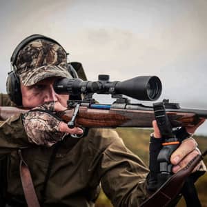 En jägare som siktar med ett Hawke Endurance 30 FD 2-12x50 kikarsikte monterat på ett jaktgevär ute i naturen.