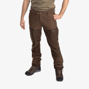 Man i bruna Pinewood Furudal Active 2L byxor sedd snett framifrån, med grön t-shirt och bruna vandringskängor, med benfickor med dragkedja och justerbara benslut