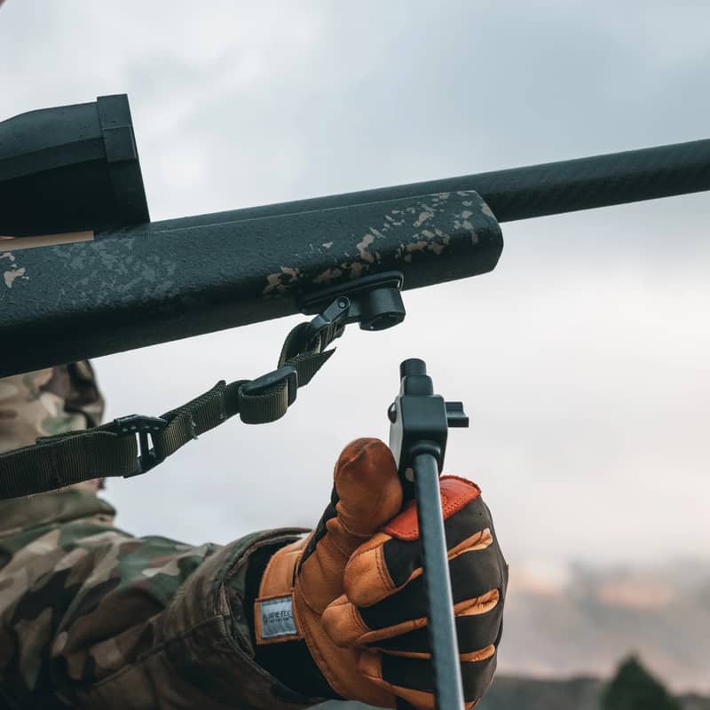 Närbild på en jägare som monterar ett benstöd i en Spartan Classic Rifle Adapter på ett gevär utomhus.