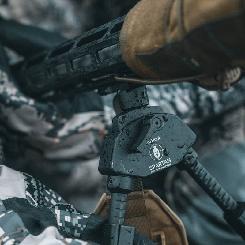 Spartan M-Lok adapter monterad på ett gevär och ansluten till ett benstöd i regniga utomhusförhållanden.