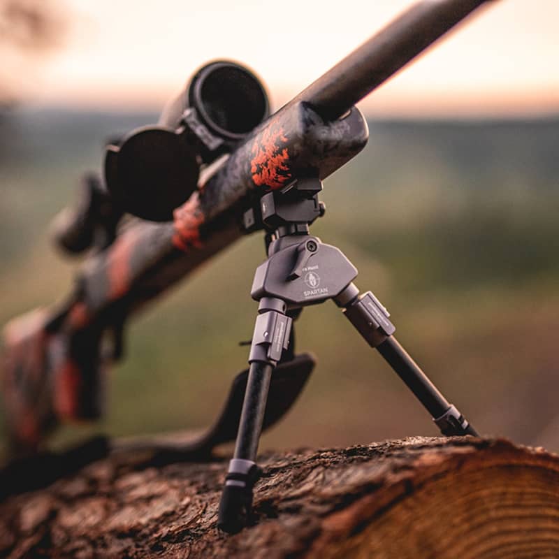 Spartan Picatinny Adapter monterad på ett gevär med bipod som vilar på en trästock utomhus