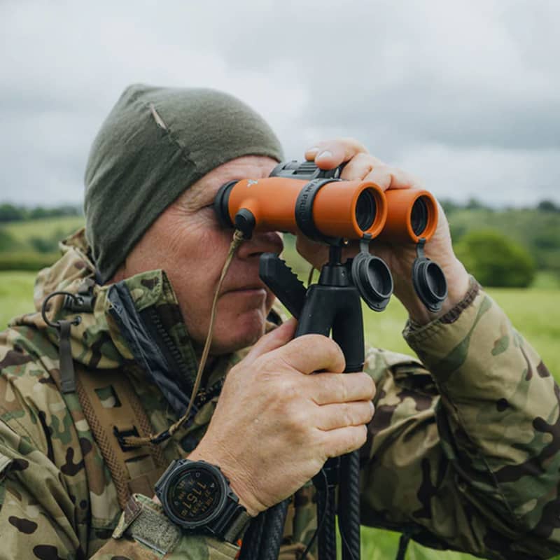 En jägare använder Spartan Springbok Quad som ett stabilt stöd för sin handkikare ute i fält.