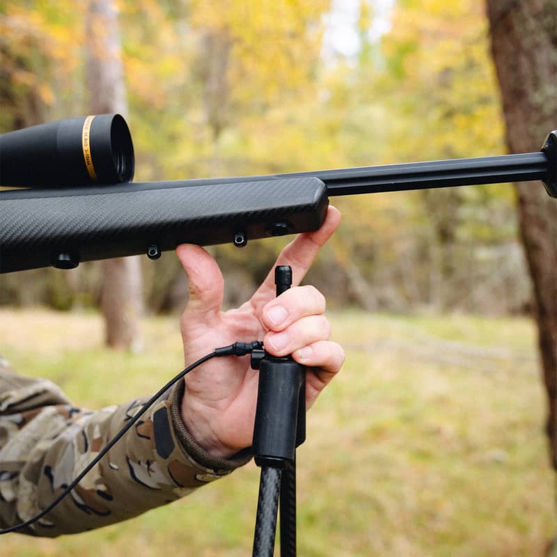 Närbild på en jägare som monterar Spartan Springbok Quad skjutstöd på ett gevär i skogsmiljö