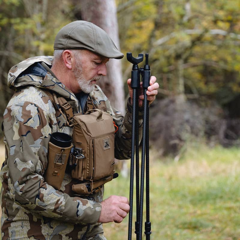 En jägare som hanterar och justerar ett Spartan Springbok Quad skjutstöd ute i skogen.