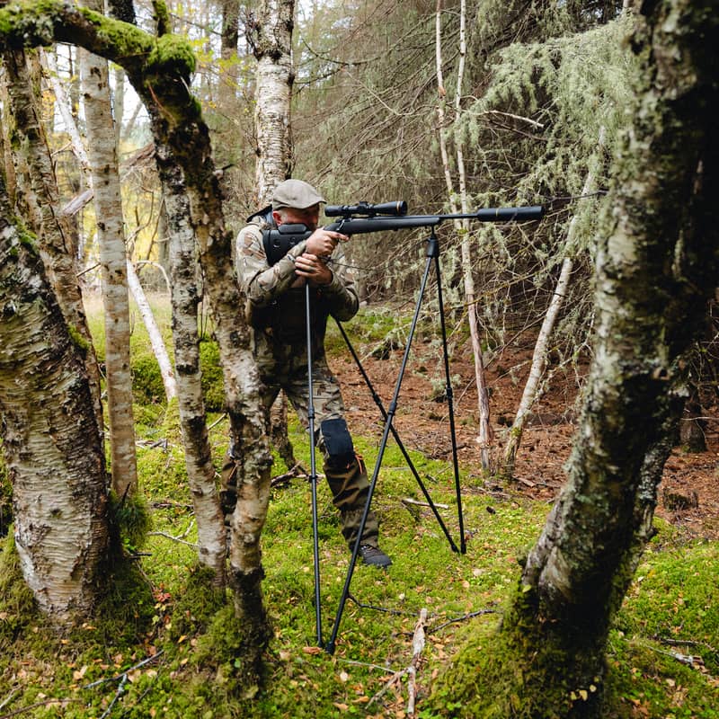 Jägare som använder Spartan Springbok Quad skjutstöd för precisionsskytte i tät skogsmiljö.