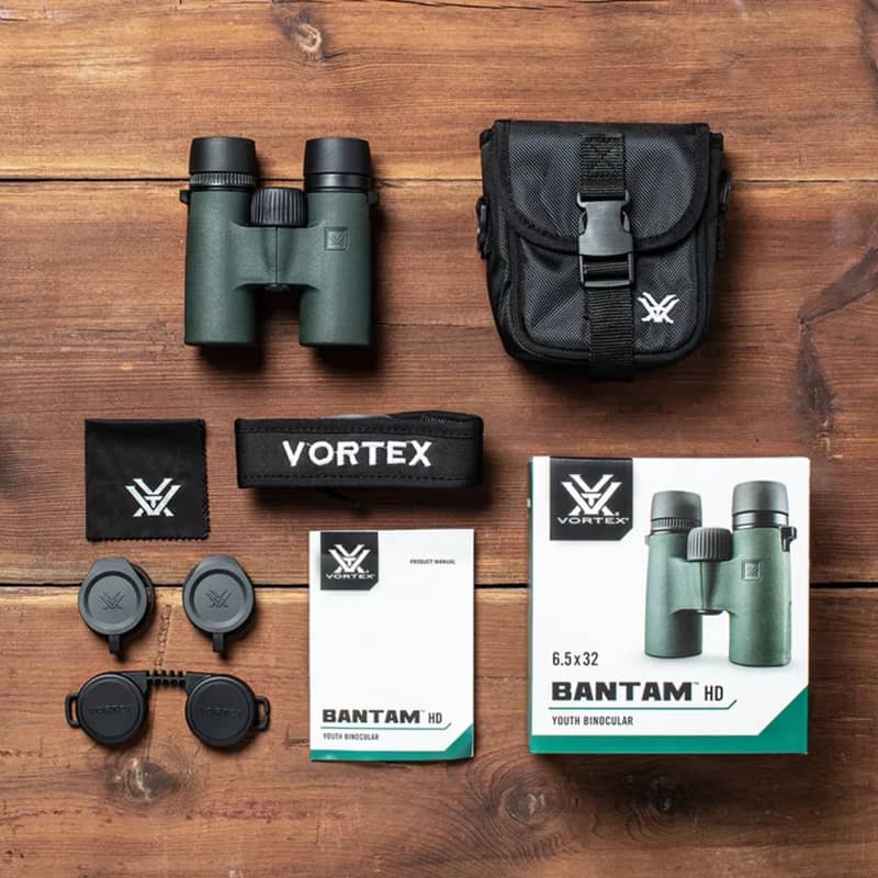 Vortex Bantam HD 6,5x32 kikare med fodral, linsskydd, rem, putsduk, manual och förpackning fotograferade uppifrån