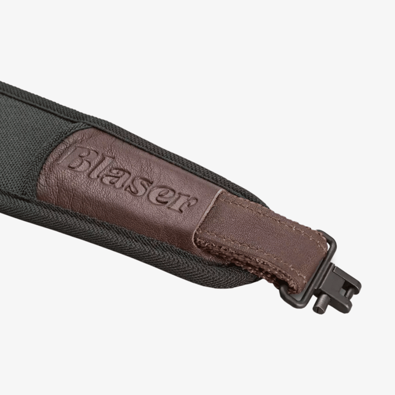 Närbild på grön Blaser gevärsrem med brunt läderparti med präglad Blaser-logotyp och rembygel med snabbfäste i metall