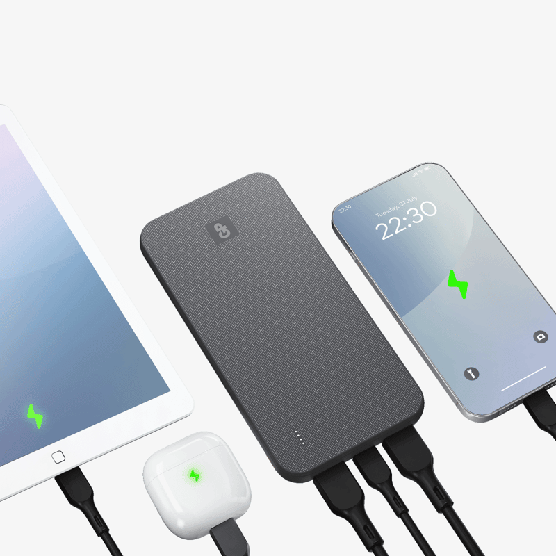 Svart GP powerbank med GP-logotyp och fyra indikeringsprickar, ansluten med svarta kablar och laddar en surfplatta, hörlurar i laddningsetui och en mobiltelefon samtidigt