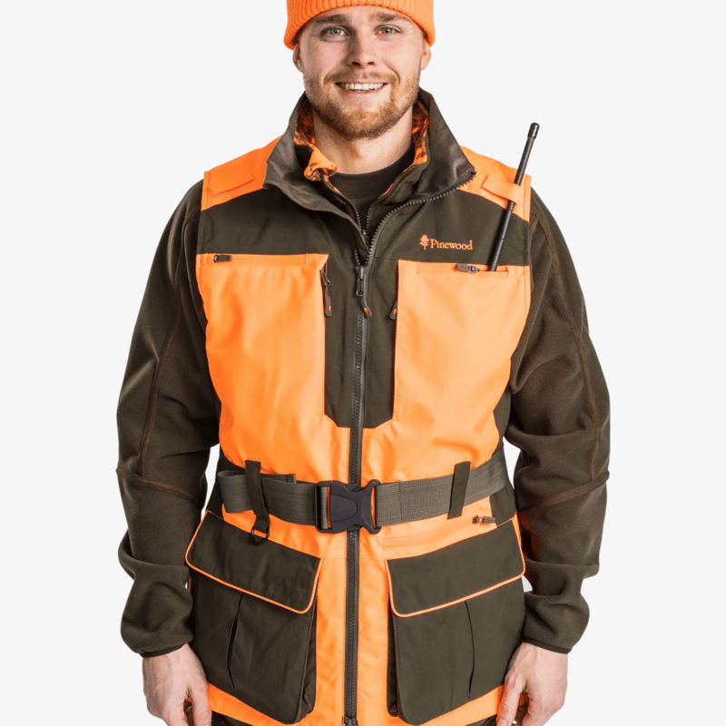Närbild framifrån av Pinewood Furudal Doghandler väst i orange och mörkgrönt med bälte och fickor, buren av modell.