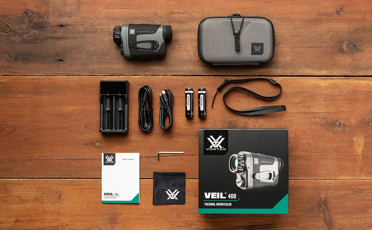 Vortex Veil 400 paketinnehåll Vortex Veil 400 termisk monokikare med fodral, laddare, batterier, kablar, handledsrem, manual och produktförpackning på träbord